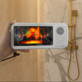 Small electronic device with a screen displaying a colorful scene, held in front of a shower.